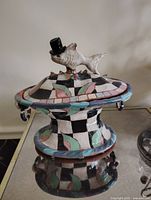 Ceramic serving dish showing the whale figurine with top hat on the lid, colorful geometric and checkered painted design