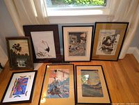Entire lot of seven framed Asian themed wall art prints, laid out on the floor near window, showing variety of styles including ukiyo-e and nature scenes.