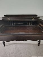 Open desk showing interior divided pigeonhole storage compartments, compartments sealed with latches, flat writing surface with wear.