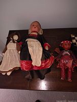 Photo showing the three antique dolls positioned side by side on a wooden surface