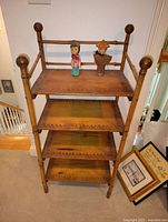 Full view of bamboo-style shelf with four shelves and two Asian statues on top.