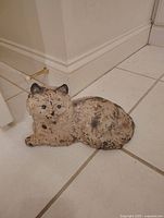 Cast iron door stopper shaped like a resting cat with a worn painted finish.