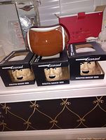 Photo of one ceramic football-shaped bowl and three boxed sculpted mascot mugs with New England Patriots branding