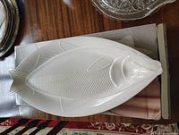 White ceramic platter shaped like a fish, showing details of scales, fins, and fish head.