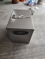 Closed metal lock box showing handle and lock with key attached.