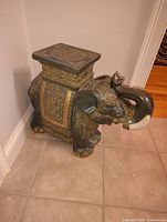 Full view of the porcelain elephant side table placed near a wall on tiled floor.