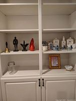 Wide view of white wooden shelves holding mixed decorative items and kitchenware.