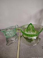 Photo showing the Vaseline uranium glass pitcher and the juicer side by side on a flat surface under normal light.