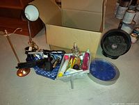 Wide view of various vintage beauty products, a small fan, and a cardboard box on the floor.