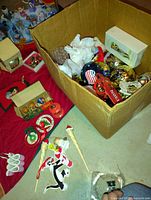 Box containing multiple colorful Christmas ornaments including gold, red, and glass baubles, candy cane hangers, and boxed items