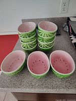 Front view of stacked watermelon bowls showing pink interior with black seed pattern and green exterior resembling watermelon rind.