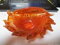 Front angle view of orange art glass bowl showing its unique wavy edges and glossy finish.
