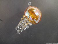 Front angle of glass jellyfish sculpture showing amber dome and clear curly tentacles
