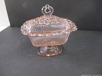 Pink glass candy dish with lace edge and lid showing profile