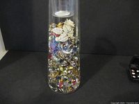 Full view of jar filled with assorted vintage craft jewelry pieces