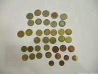 Overview of all coins spread out on white surface showing a variety of Euro denominations including small and larger coins.