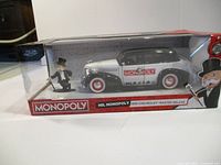 Boxed die cast model car with Mr. Monopoly figure visible inside packaging.