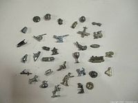 Photo showing 34 metal Monopoly tokens arranged randomly on a white background.