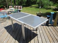 Photo of the patio table in extended position showing two glass top panels and aluminum frame.