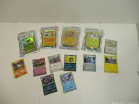 Five unopened Pokemon booster packs and nine loose Pokemon cards laid out including several holographic and rare editions.