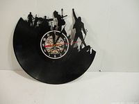 Overall view of the black vinyl record clock featuring rock band cut-out silhouette and central clock mechanism.