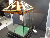 Tiffany style stained glass display cabinet showing the stained glass roof and clear glass sides with the black base.