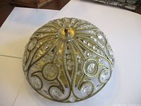 Top and side views of the rounded dome ceiling light fixture showing intricate bead patterns and metal central piece.