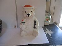 Front view of the Coca Cola polar bear cookie jar showing the bear holding a Coca Cola bottle and a smaller bear with a red nose, wearing a Santa hat and scarf.