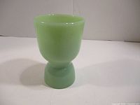 Side view of the vintage jadeite egg cup showing the shape and color.