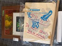 Photo showing framed artwork with brown frame with paper envelope labeled 'Do Not Bend' on top