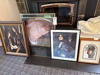 Four framed artworks leaning against a fireplace showing different subjects and sizes.