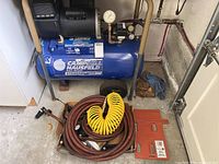 Full view of Campbell Hausfeld Standard Duty air compressor unit with coiled yellow and brown air hoses, showing overall condition and setup.