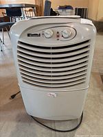 Front view of Kenmore dehumidifier showing control knobs and vented grill, power cord coiled underneath.