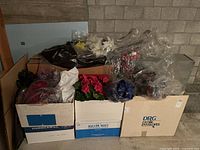 Boxed faux floral arrangements including red and blue flowers in plastic and loose bunches.