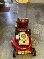 Full front view of the red Toro gas lawn mower showing the handle, wheels, and red cutting deck marked '19' with the Toro brand label.