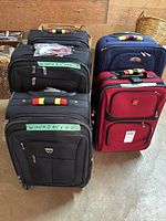 Photo showing five luggage pieces: three black Travelpro, one blue Air Canada, one red Swiss Gear, with green tape labels showing measurements on some suitcases.