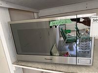 Front view of Panasonic microwave showing reflective silver door, keypad, and size label 20 x 15 x 12 inches.
