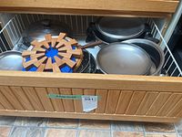 Drawer filled with various metal pots, pans and wooden trivets.