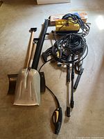 Full lot layout showing the Karcher pressure washer unit, several hoses and lance attachments, two shovels, long black bag, and cardboard box with manual on top.