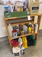 Front view of wood shelving unit containing multiple bottles and containers on three shelves for size reference.