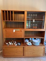 Full view of assembled two-piece teak cabinet showing shelving configuration, wine rack, glass door, drop-front and sliding door compartments