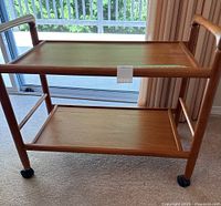 Full view of two-tier teak trolley on caster wheels