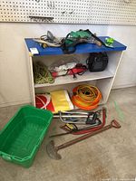 Full lot view showing cabinet, tools, extension cords, and garden tools spread on and around cabinet.