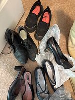 Photo displaying various women’s shoes including black slip-on sneakers, black lace-up shoes, black Mary Jane flats, and black heels.