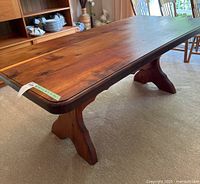 Full view of the solid yellow cedar table showing its large rectangular top and two carved pedestal legs.