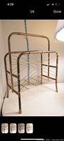 Front view of brass magazine holder with curved handles and wire racks showing patina finish.