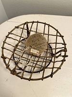 Front angle view of small vintage brass wire basket with a paper tag inside showing price and description.