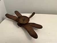 Photo showing a rust-colored cast iron tealight holder shaped like a dragonfly, placed on a white surface.