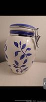 Photo showing side view of blue and white ceramic cookie jar with leaf design and hinged lid closed