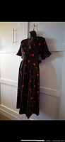 Side view of the black dress with red hearts showing sleeve detail and mid-length skirt